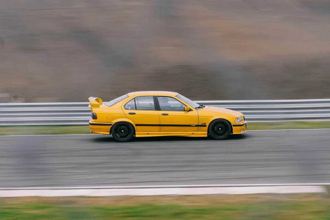 Voiture de sport jaune photographiée en filé sur un circuit, glissière et décor étirés par le mouvement