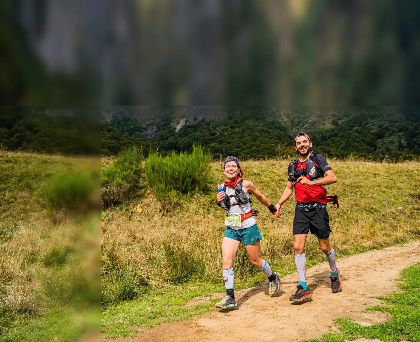 Trail du Sancy, vallée de Chaudefour : une coureuse au dossard 1566 et son compagnon courent main dans la main devant les crêtes